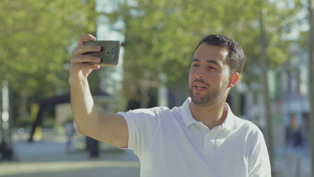 Blogger barbudo alegre gravando vídeo com o smartphone.