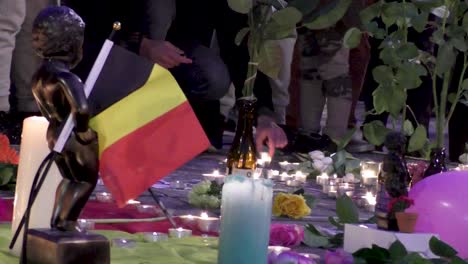 people paying tribute after brussels terror attacks - candles, flowers, manneken pis statue with belgian flag - march 22 2016 - brussels, belgium