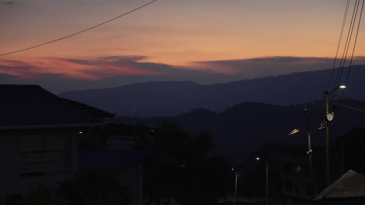 Sunset sunrise over a mountain range building and power lines in the foreground