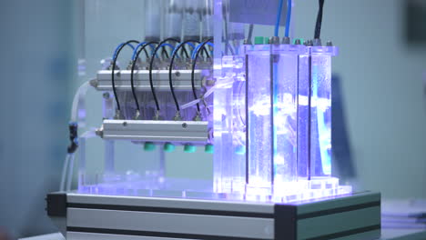 burbujas de gas hidrógeno en tubos con agua en un demostrador de electrolizadores, luz azul, tuberías