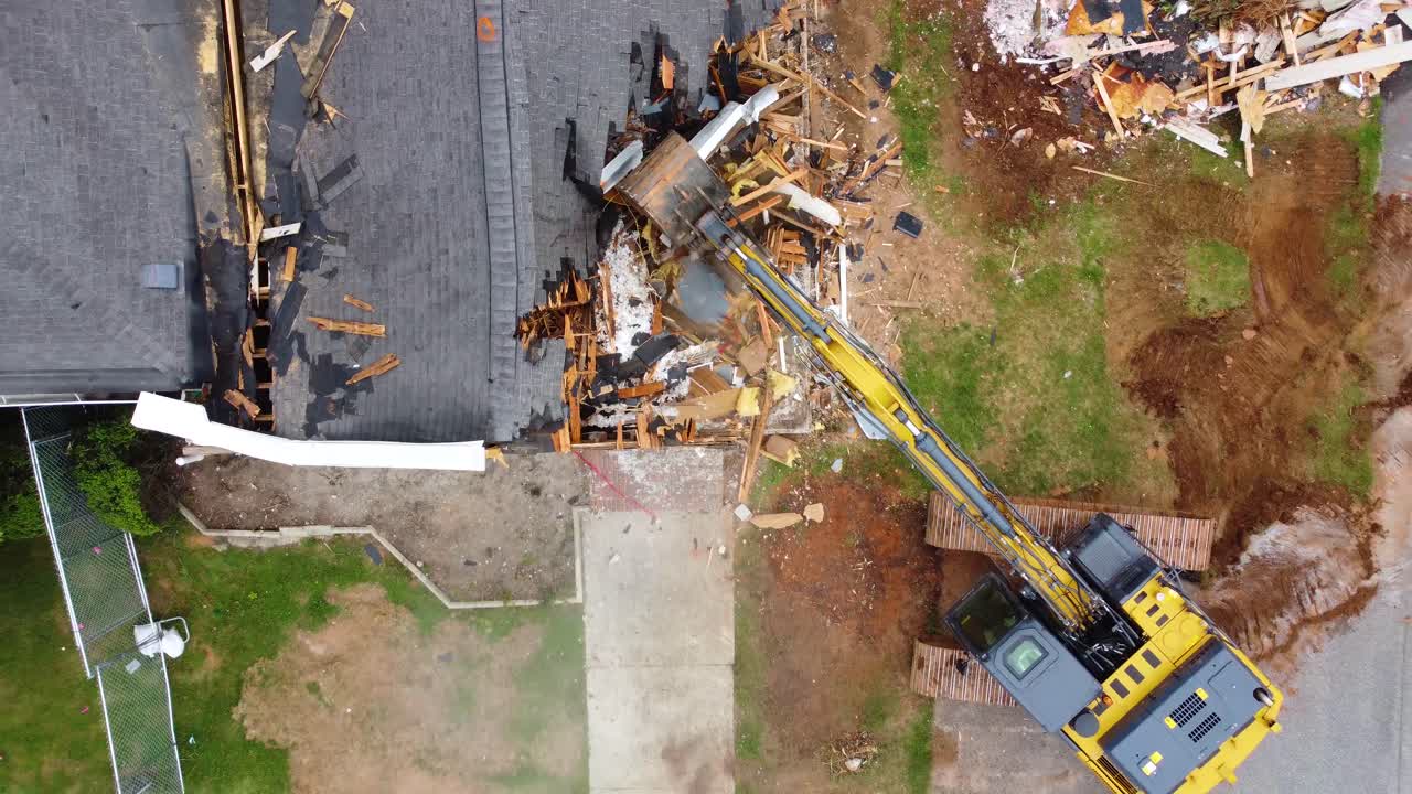 un disparo de avión no tripulado de arriba hacia abajo de un excavador que comienza a derribar un edificio