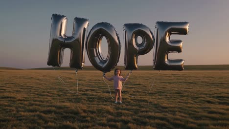 child holding hope balloons in a field at sunset