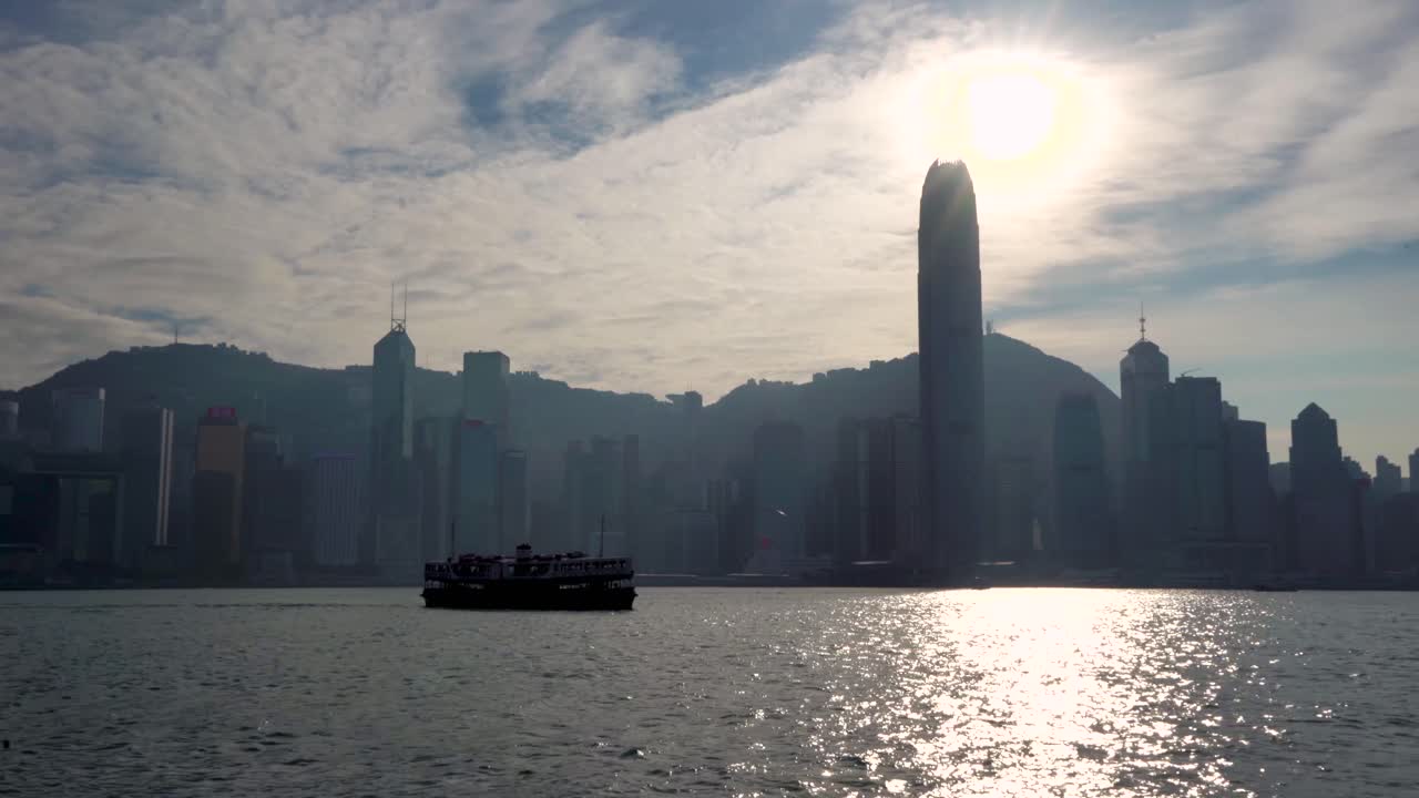 bella y famosa silueta del horizonte de la megaciudad de hong kong, histórico barco de ferry estrella navegando a través del puerto marítimo de victoria en el cálido y soleado día de verano del cielo azul, sol brillante que se refleja en el agua