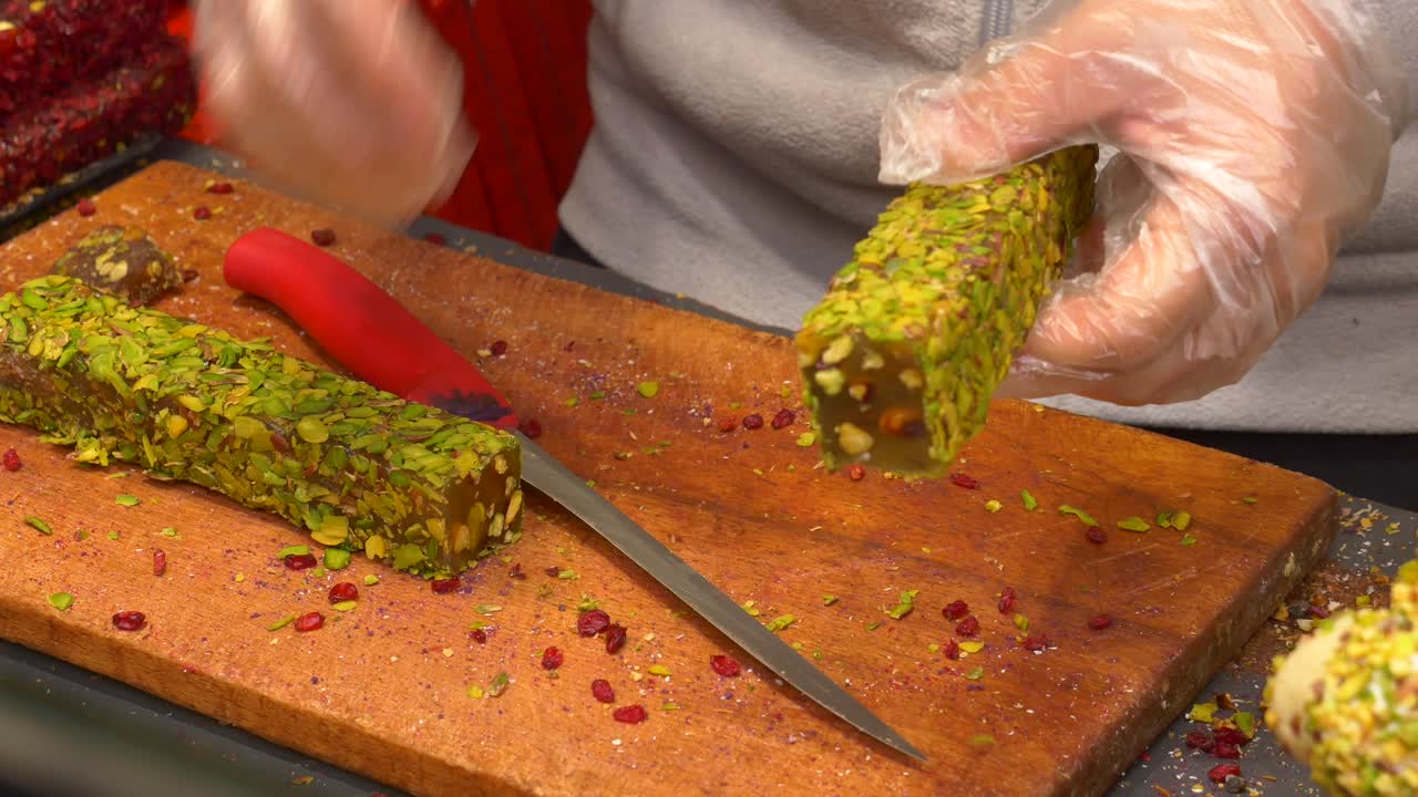con guantes cortando un bloque de delicias turcas con pistacho