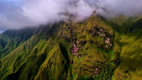 aerial shot with the drone flying closer to the majestic, mist-covered green mountains of bukit selong
