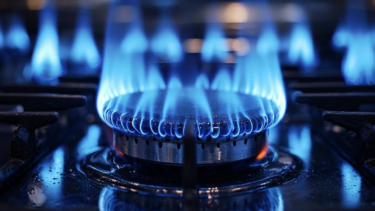 Blue flames from a gas stove burner. Bright blue flames dance from a gas stove burner in a modern kitchen during evening cooking preparations.