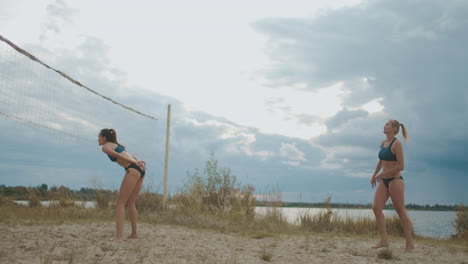 mujeres jóvenes activas están jugando voleibol de playa en verano en clima nublado saltando y corriendo sobre la cancha de arena estilo de vida saludable