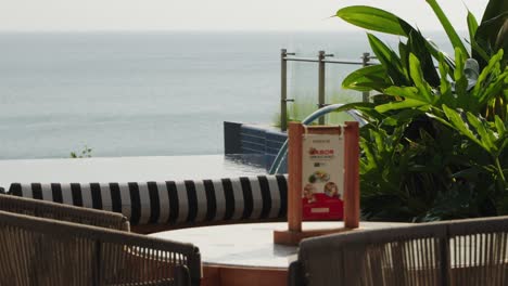 table and chairs in rooftop garden restaurant with sun shinning in reflecting off the infinity pool