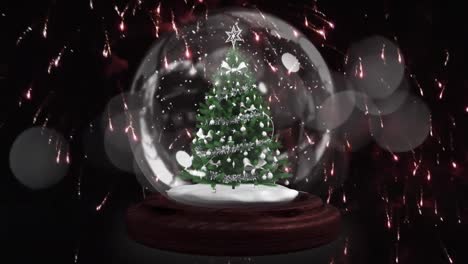 estrella fugaz alrededor del árbol de navidad en un globo de nieve contra fuegos artificiales explotando en fondo negro