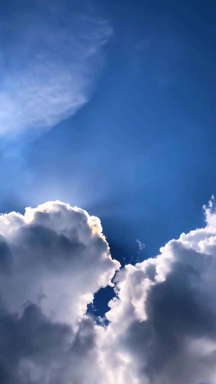 Raggi di sole e nuvole bianche che si muovono attraverso un cielo blu