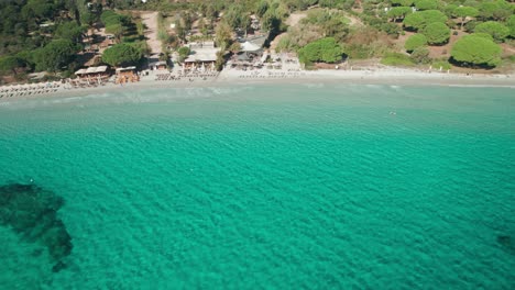Luft--Und-Drohnenaufnahmen-Eines-Strandes-Mit-Liegestühlen-Und-Türkisfarbenem-Wasser,-Korsika