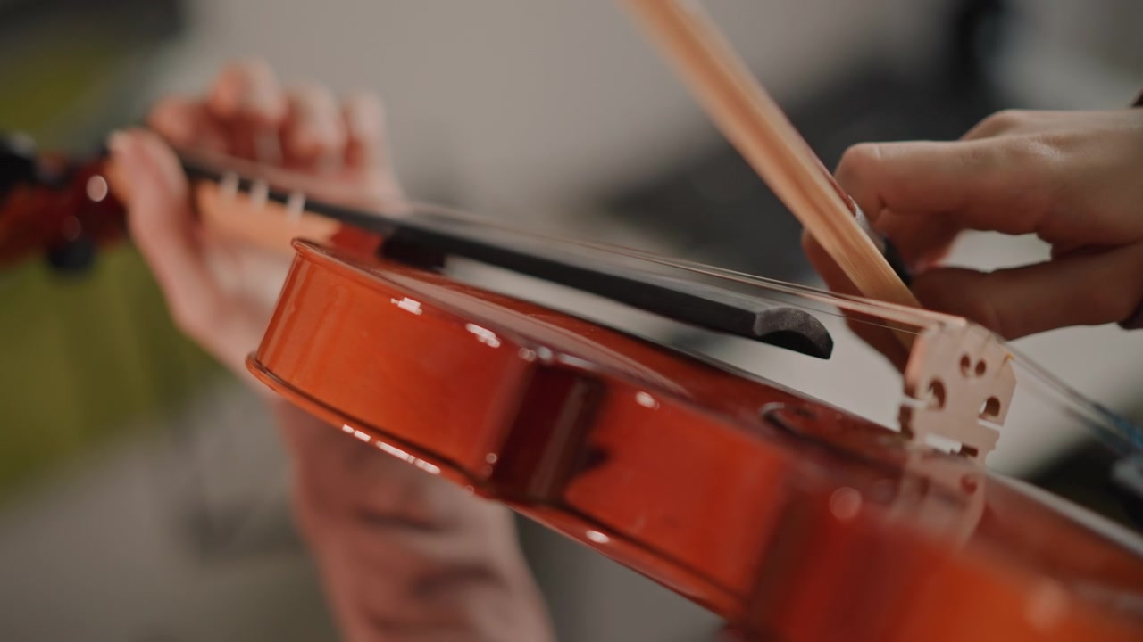 Detailed bowing technique on violin strings, closeup of bow stroke and hand coordination, slow deliberate motion showing dynamics and articulation, practice session with focused coachlike instruction