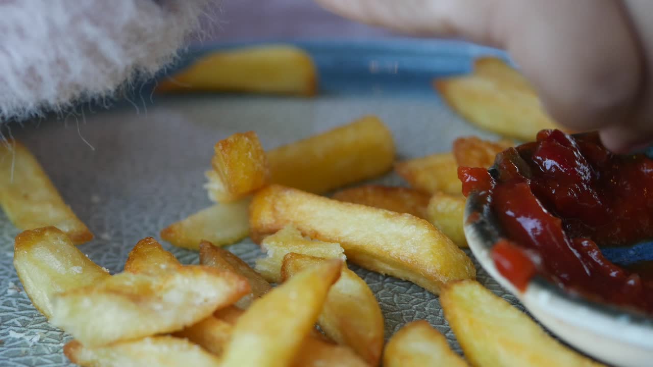 Mano di bambino che si allunga verso patatine fritte con ketchup