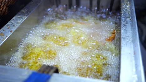 Food-frying-in-frying-oil-in-commercial-restaurant-kitchen,-close-up