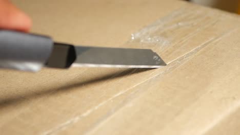 opening a cardboard box with a utility knife