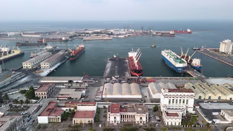 aerial view of a busy commercial port with cargo ships docked and city infrastructure