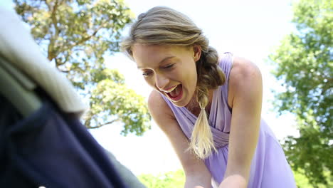 mother tending to her baby girl in her pram in the park