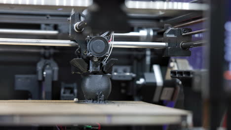 a close-up view of a 3d printer in operation, fabricating a black object