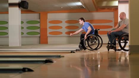 two young disabled men in wheelchairs playing bowling in the club