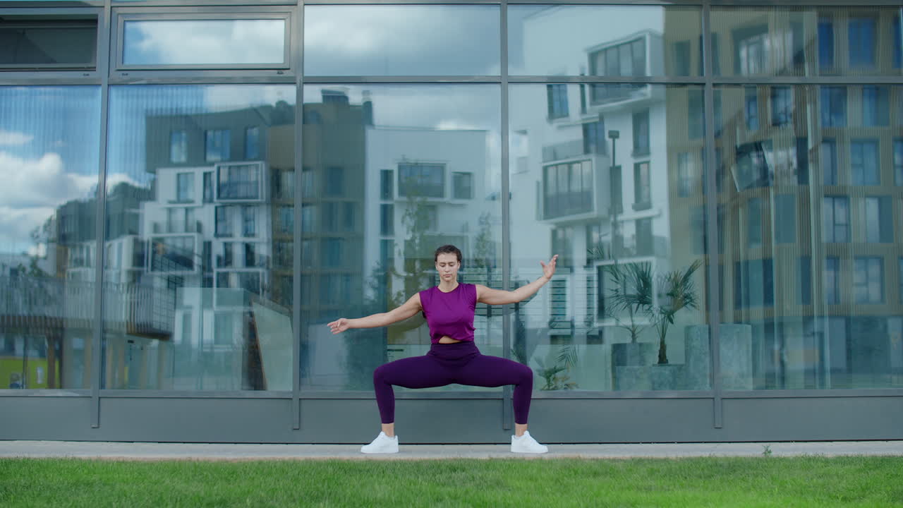 Woman doing yoga outdoors in front of a modern building