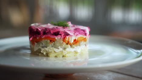 ensalada rusa tradicional con remolacha y verduras de arenque, en una mesa de madera en un plato blanco