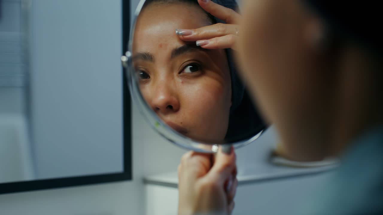 Donna che si controlla la pelle allo specchio del bagno