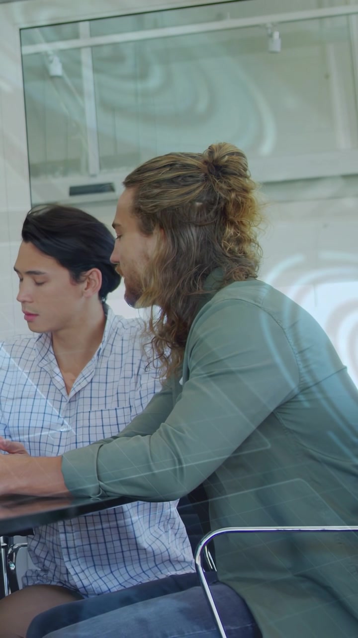 Video verticale: Due colleghi chinati su un tablet in un contesto lavorativo, il cui sguardo attiva tag animati per la revisione.