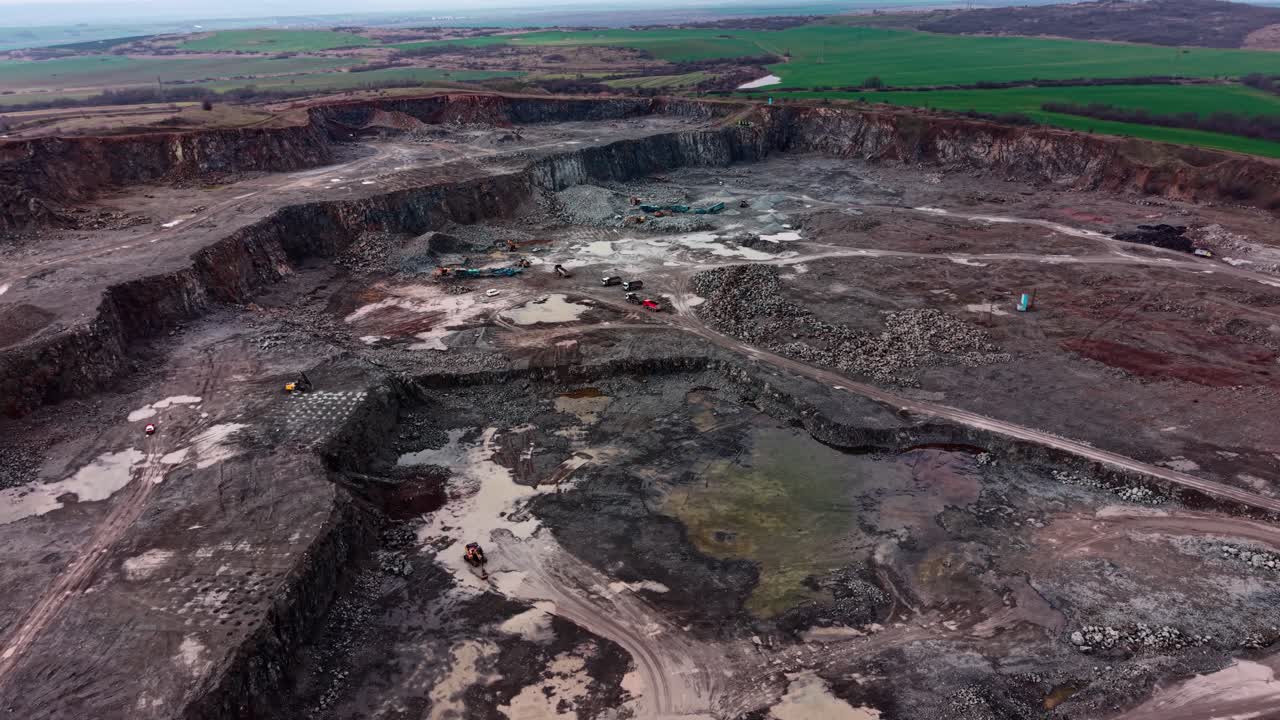 Granite quarry site with machinery in operation near open fields