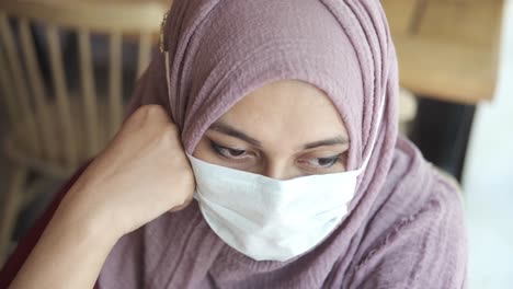 mujer con hijab y máscara, mirando pensativa