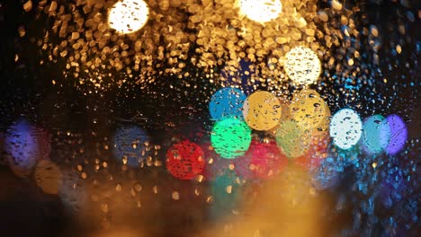 multicolored lights of the night city and passing cars through the glass of car in drops of rain. abstract bokeh autumn rainy city background