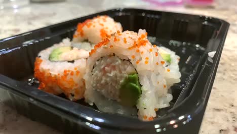 small hand picking up a sushi roll. take out sushi. california rolls