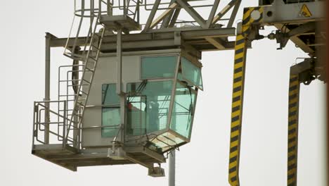 Crane-operator-cabin-at-industrial-port,-overcast-day,-close-up