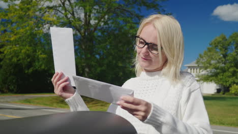 woman collects letters from a mail box