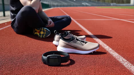 athlete resting on a running track with running shoes and sport tracker