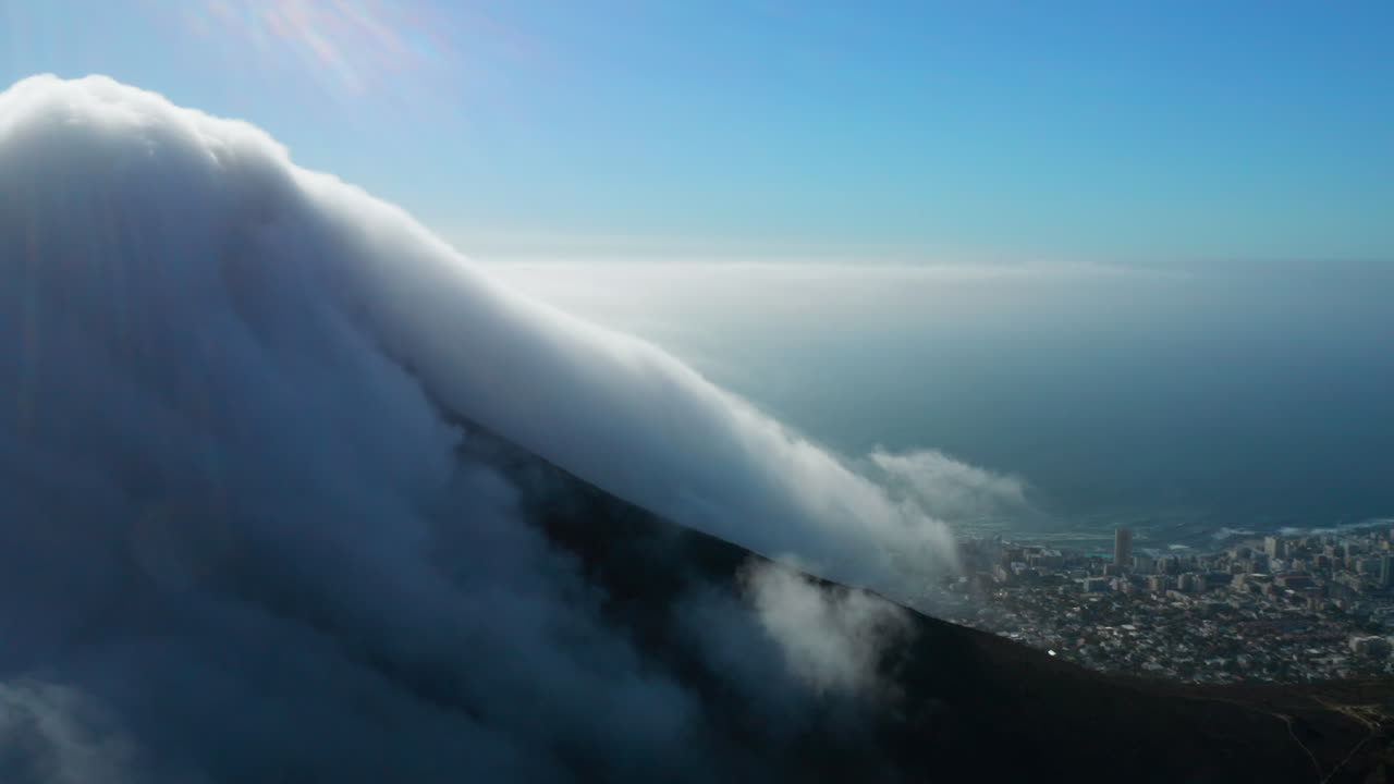 Aerial pan shot of Lion's Head with lots of clouds and a beautiful view of Seepunt in Cape Town, South Africa
