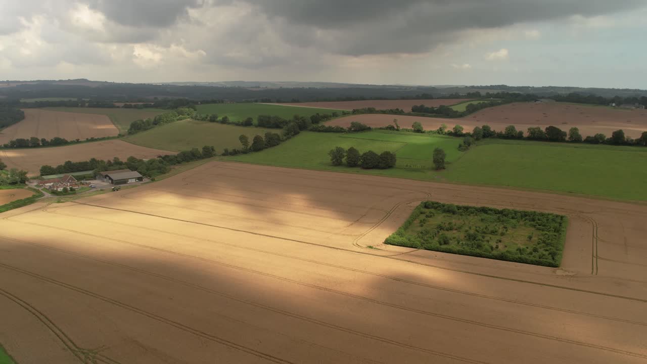 Aerial view establishing overcast rain clouds casting shadows over Devizes agricultural farmland