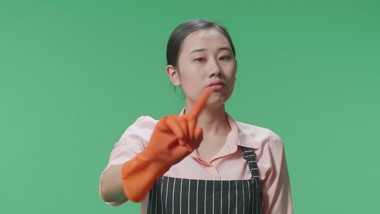 녹색 스크린 스튜디오에 서 있을 때 손가락을 흔들고 있는 아시안 여성 집주인