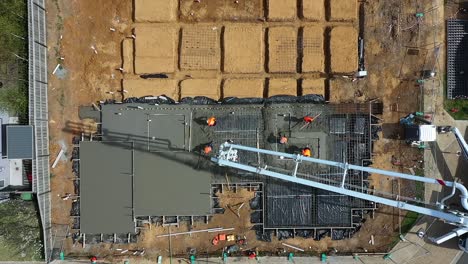 aerial directly above cement pump pouring concrete onto new estate