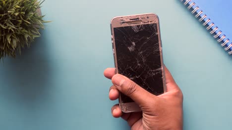 a person is holding a broken phone with a cracked screen.