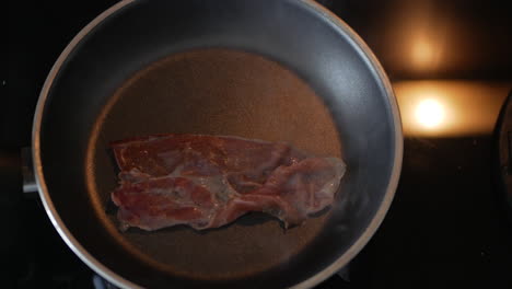 cooking bacon slice in a hot skillet - overhead shot, timelapse