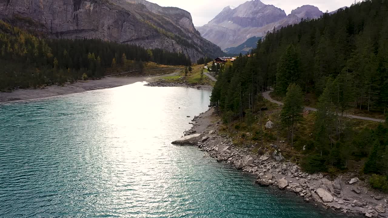 vista aérea de las montañas, el bosque otoñal y el reflejo del sol en el lago glaciar turquesa oeschinensee