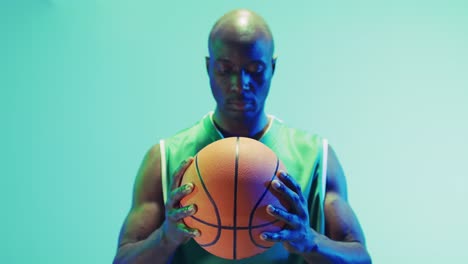 Video-Des-Porträts-Eines-Afroamerikanischen-Männlichen-Basketballspielers-Mit-Ball-Auf-Blauem-Hintergrund