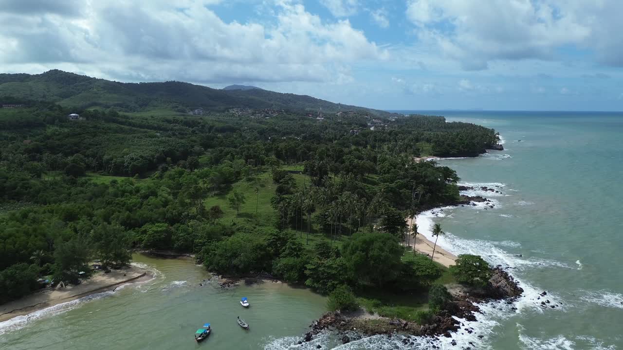 Drone footage showing lush green palm trees, tropical forest and rocky coastline with hidden sandy beaches on Koh Lanta island, Thailand, overlooking the turquoise Andaman Sea
