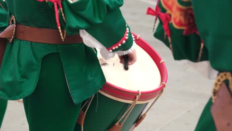 drummer in traditional costume playing on drum during street festival celebration