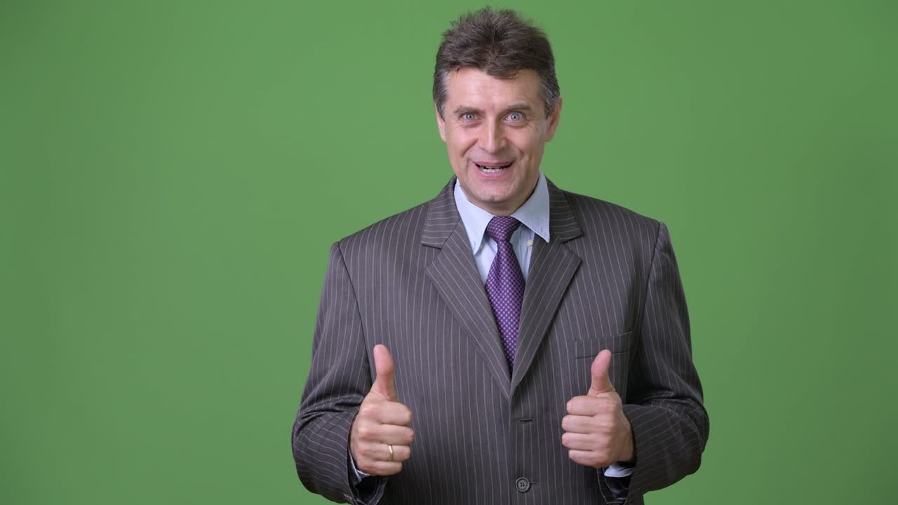 hombre de negocios maduro y guapo contra un fondo verde