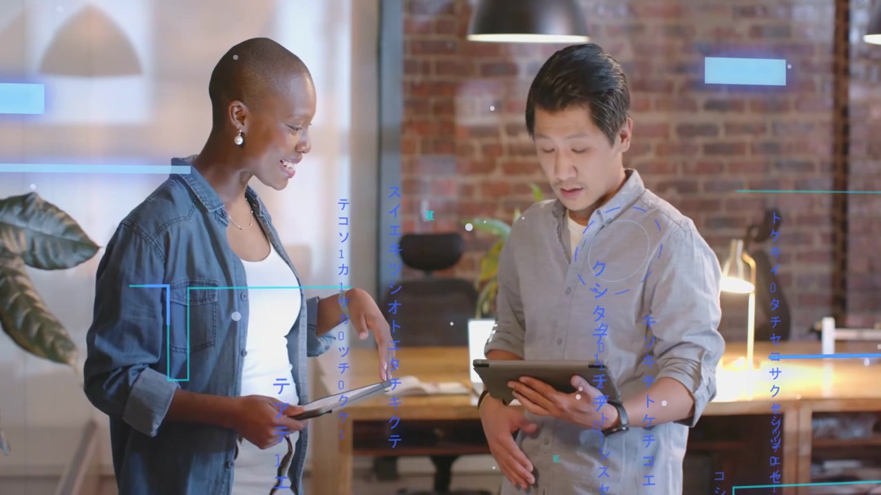 Man gesturing with tablet, woman comparing screens while blue charts on screens aiding design work