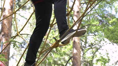 person walking across rope net in forest