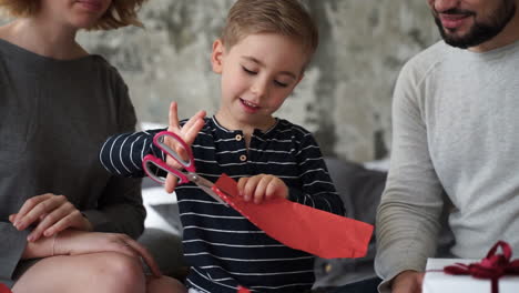 small child cuts with scissors paper for wrapping christmas presents