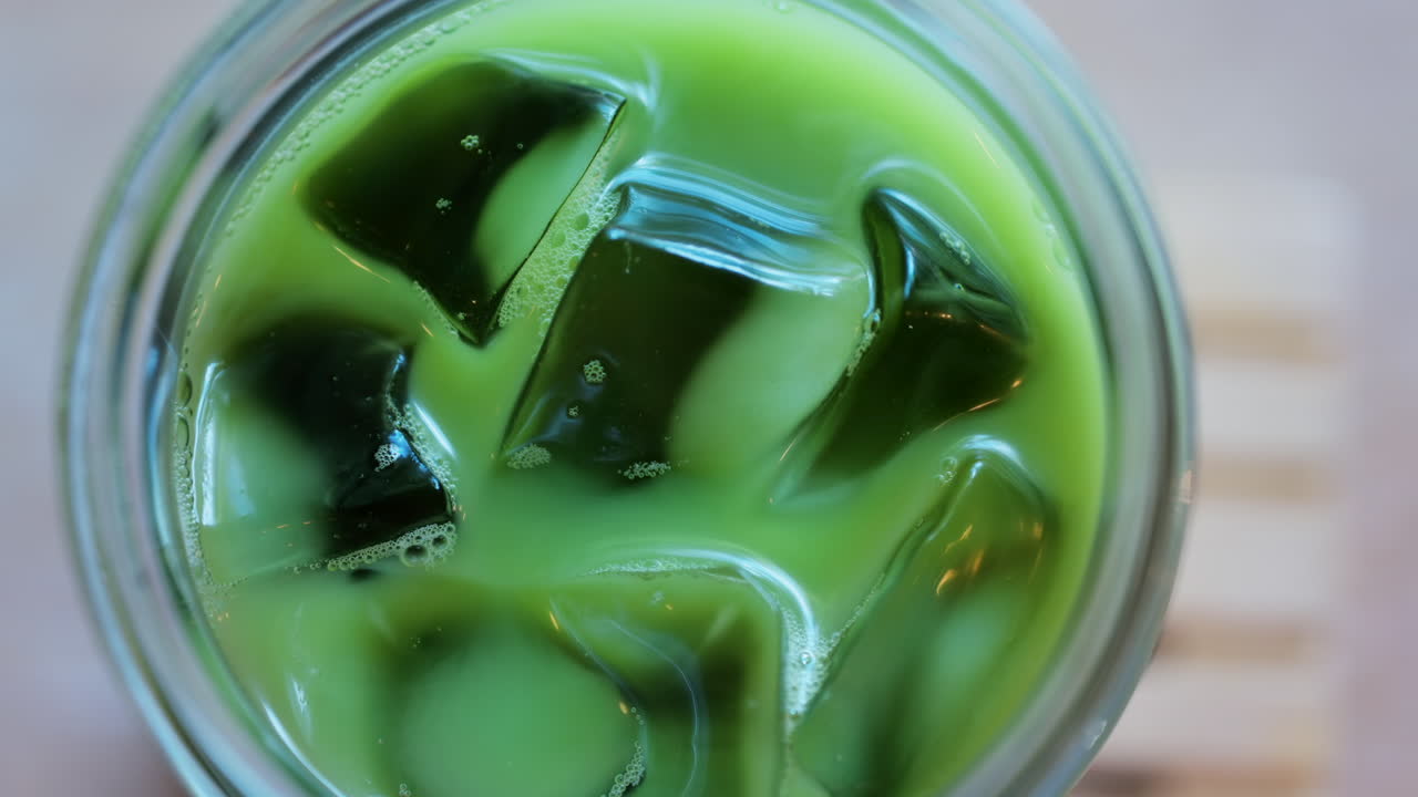Close up of a glass of an iced matcha on a table at a cafe