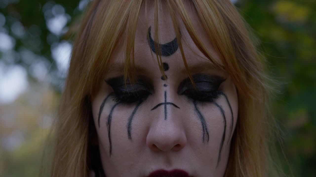Beautiful Witch smiling in an evil way to the camera and turning around in the cemetery, slow motion Close up